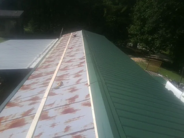 Old rusted panels beside newly installed green metal roofing — Wind Damage Roof Repair by Roofing Brothers in Universal City