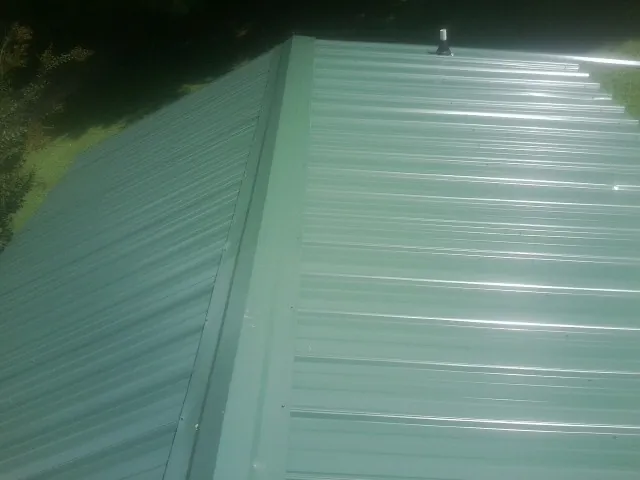 New green metal panels meeting at the ridge of a roof — Flat Roof Repair work by our crew in Universal City