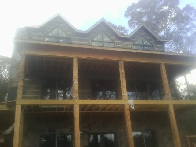 Dormers and porch framing on a large log home under construction — Roof Coating work by our crew in Universal City