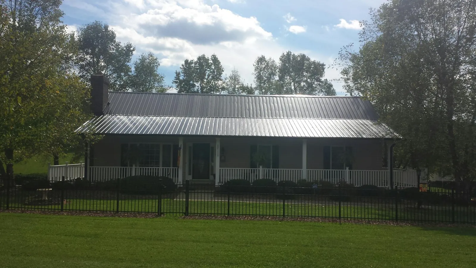 Gray metal roof on a brick ranch with a full width front porch — Gutter Guard Installation work by our crew in Universal City